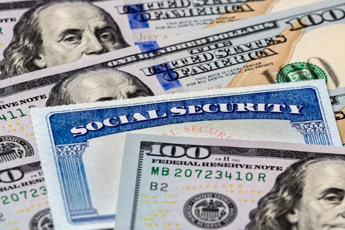 Social Security card surrounded by cash, representing retirement income, disability benefits, or government assistance.