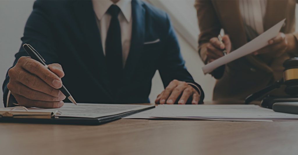 Lawyers reviewing legal documents at desk with gavel in professional legal office setting.