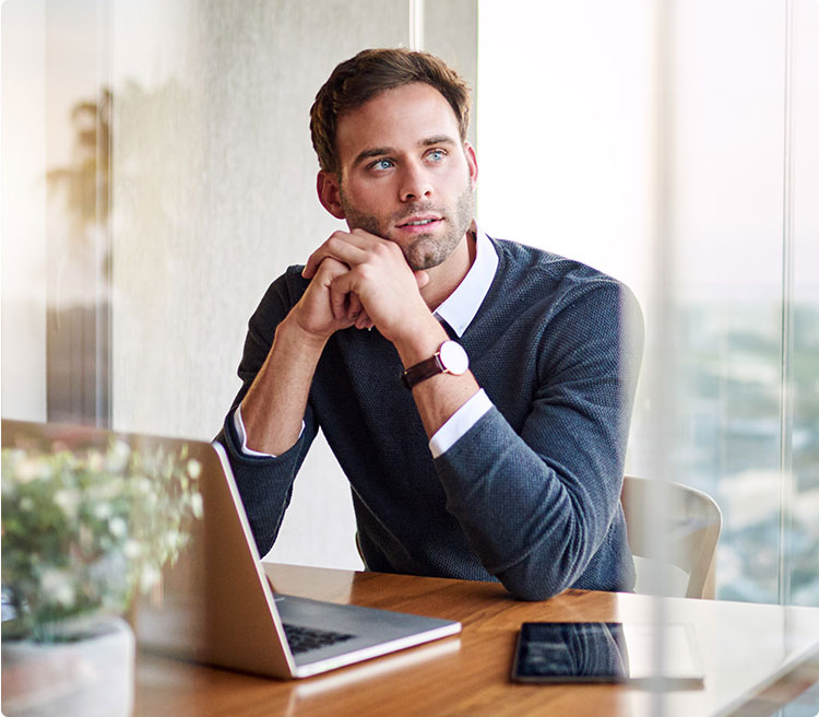 Thoughtful man sitting at desk with laptop, considering bankruptcy options in a modern office.