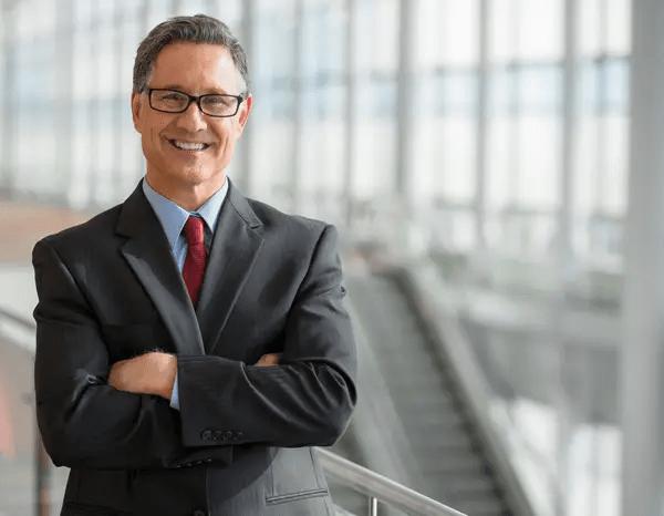 Confident attorney in business suit smiling with arms crossed in modern office setting.