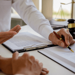 Young male lawyer in a modern law office standing at a desk with legal documents, a gavel, law books, and Lady Justice statue.