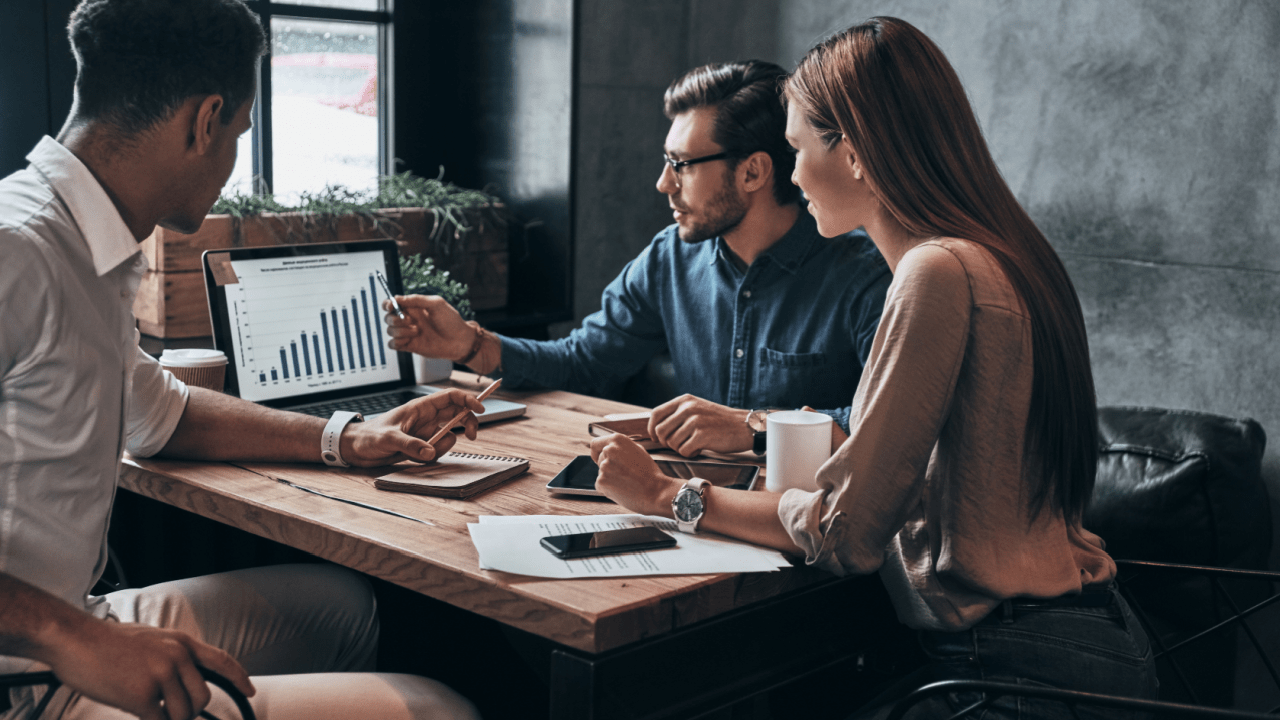 Business professionals analyzing high-ticket lead generation data on a laptop, comparing lead costs across legal, finance, and real estate industries.