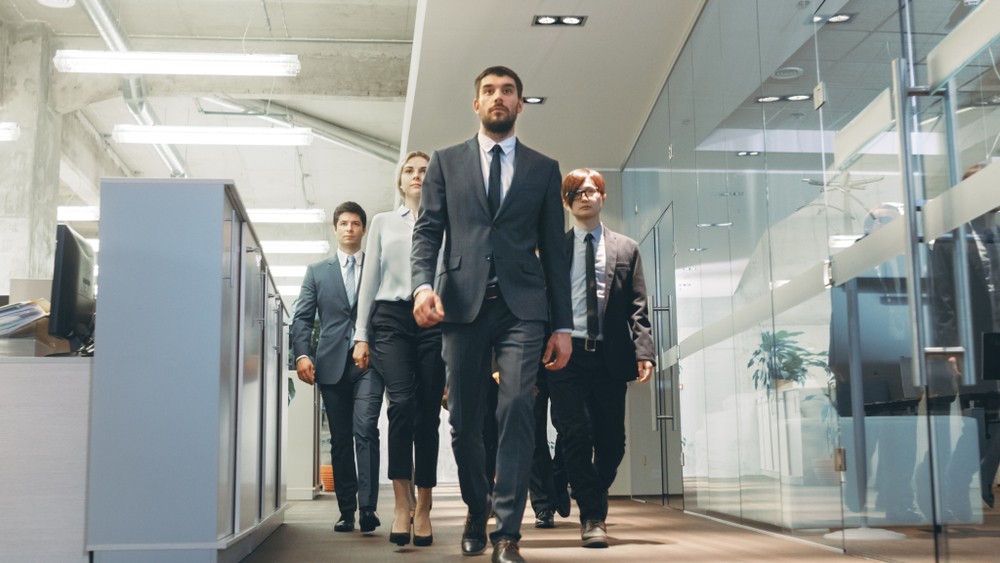 Confident legal team walking through modern office hallway