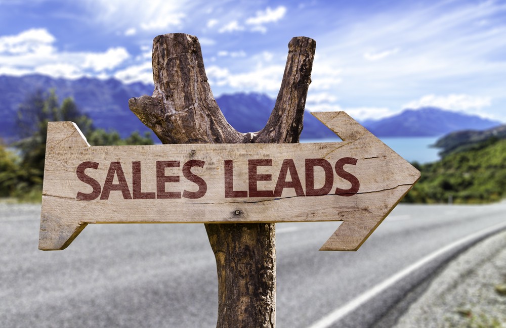 Wooden sign with "Sales Leads" pointing down a scenic road