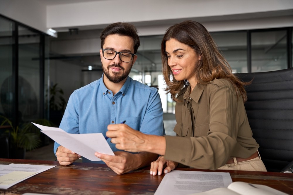 Two professionals reviewing documents together in a modern office setting
