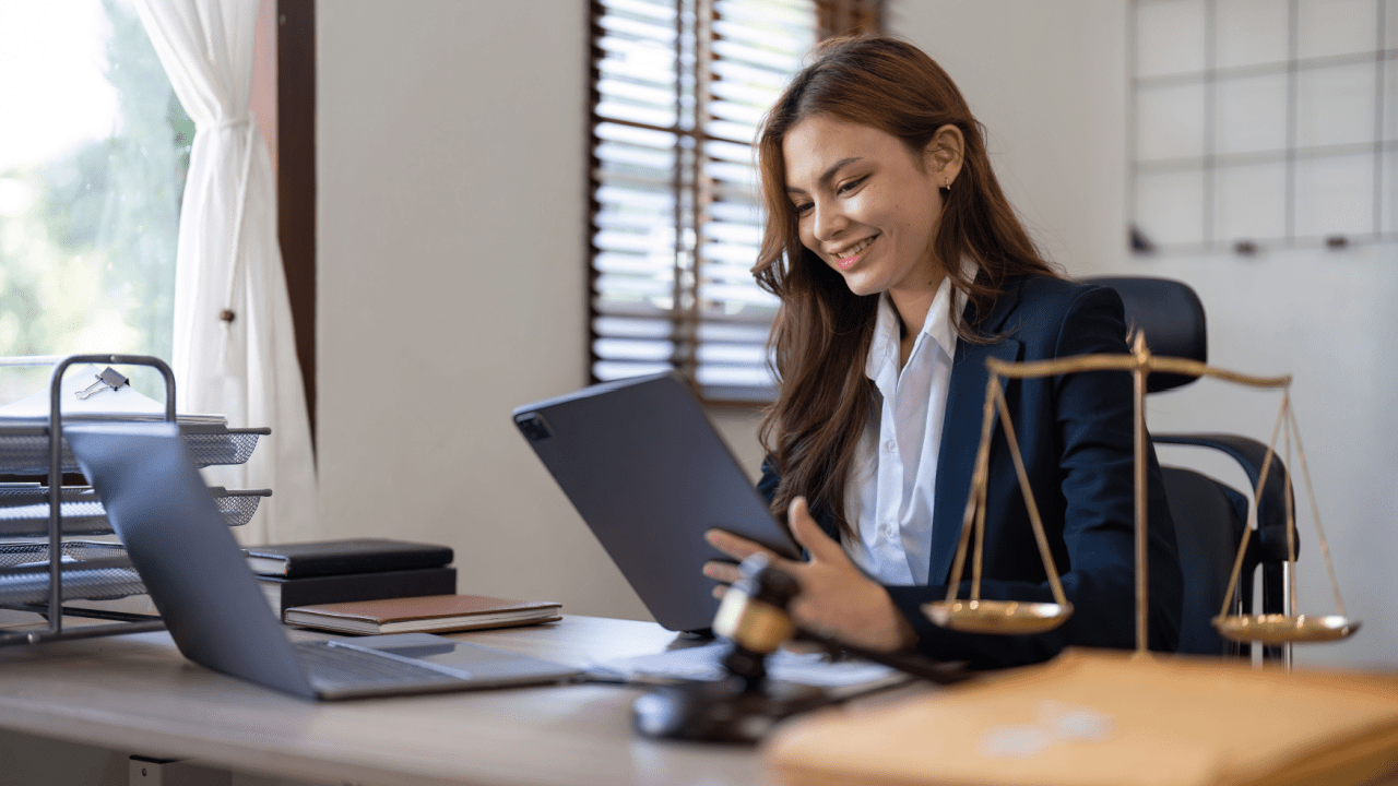 Female attorney smiling while working on tablet in office