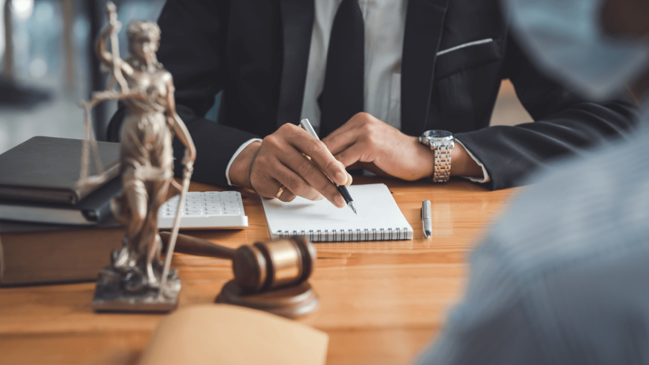 Bankruptcy attorney writing notes at law office desk with Lady Justice statue and gavel, demonstrating whether bankruptcy law is in demand